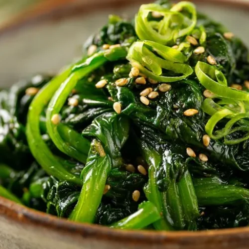 sauteed spinach with sesame seeds and green onions in a bowl