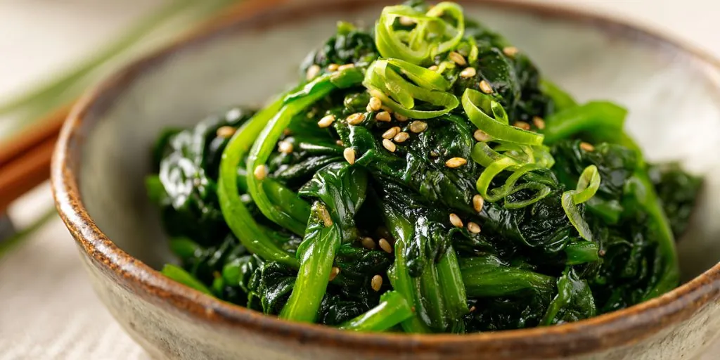 sauteed spinach with sesame seeds and green onions in a bowl